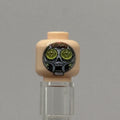 A custom-printed LEGO minifigure head with a beige skin tone, featuring a black and white skull design with green circular eyes and the text 'Pringles' on a gray background.