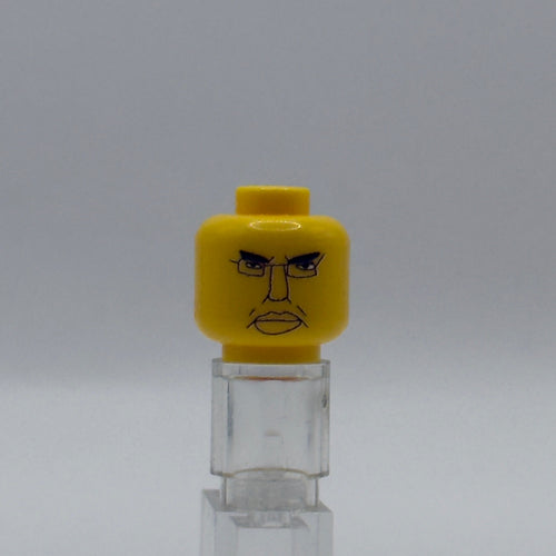A yellow LEGO minifigure head with an angry printed face, displayed on a clear acrylic stand against a neutral gray background.