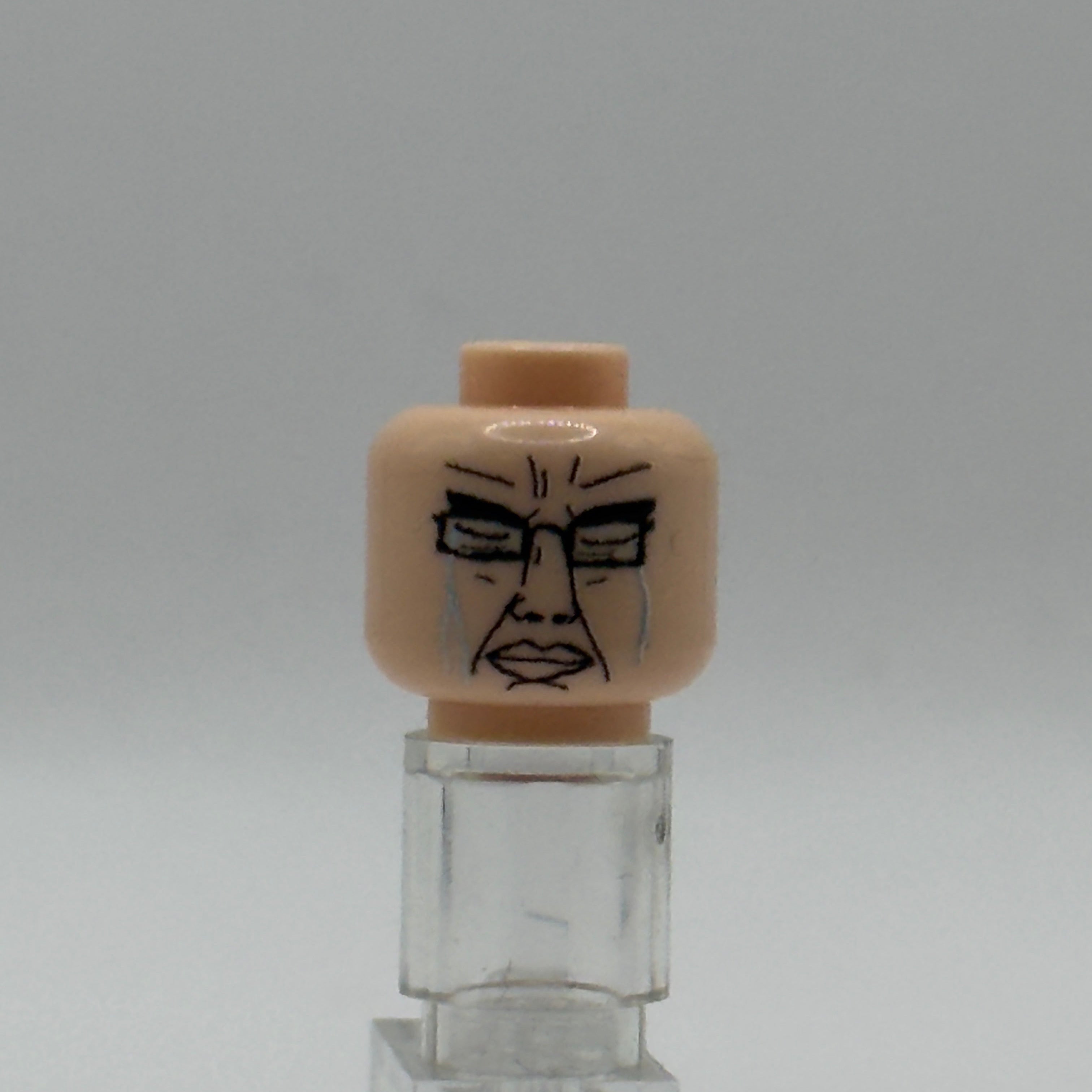 A custom printed LEGO minifigure head with a black face design, displayed on a clear plastic stand against a neutral gray background.